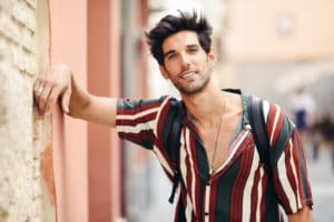 Attractive young man with dark hair and modern hairstyle wearing casual clothes outdoors