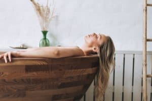 Blonde smiling sensual young woman 35 year plus with long hair takes wooden bath relax at spa salon