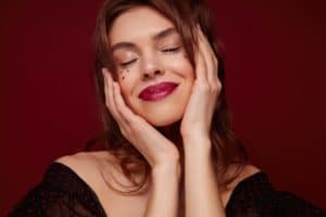 Enjoyable young brown haired pretty woman with red lips and little silver stars on her face