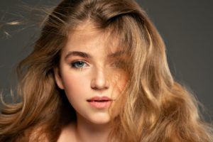 Pretty young woman with long brown hair looking at camera.