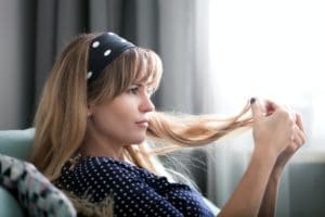 Woman at home looking at her hair, checking hair condition