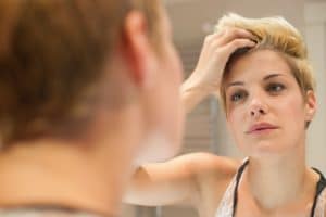 Woman examining herself in mirror