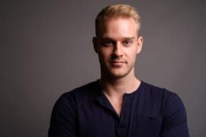 Young handsome man with blond hair against gray background